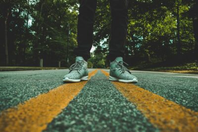 feet with sneakers straddling the centerline of a road